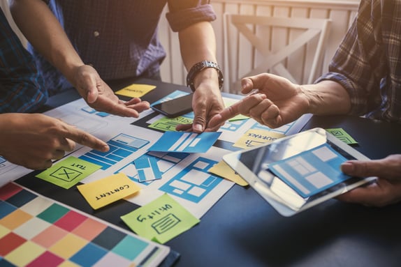 Team collaborating on UX and marketing strategy with wireframes and AI-driven planning.
