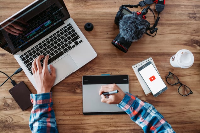 Digital marketer using laptop and tablet for AI-powered content creation and campaign planning.