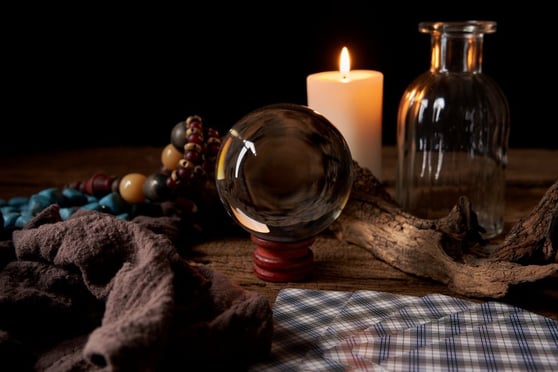 Crystal ball with candle, beads, and glass objects, symbolizing future trends and predictions.