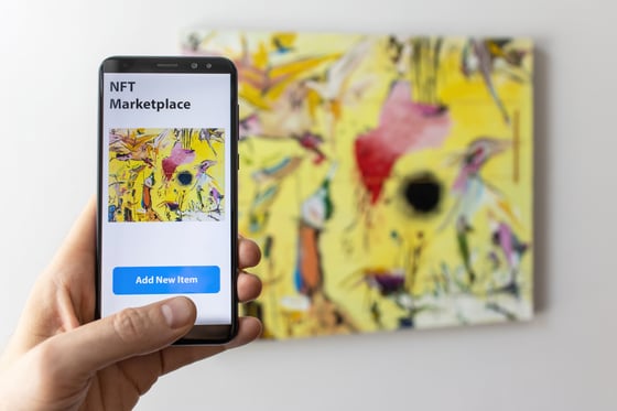 Person using a smartphone to add digital artwork to an NFT marketplace.