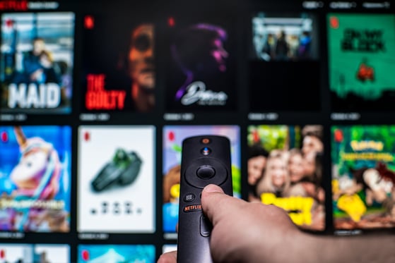 Person using a streaming service remote to browse TV and movie content.