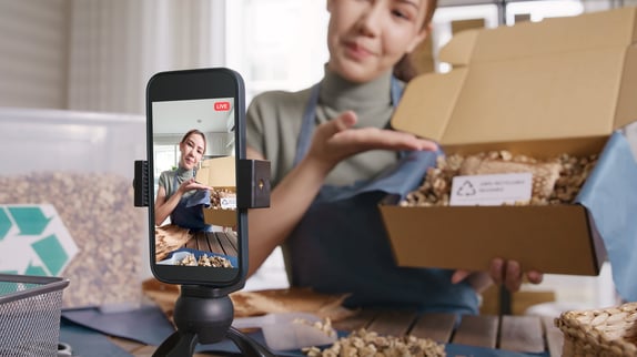 Creator filming a live product demo on a phone, showing how video commerce builds trust and visibility.