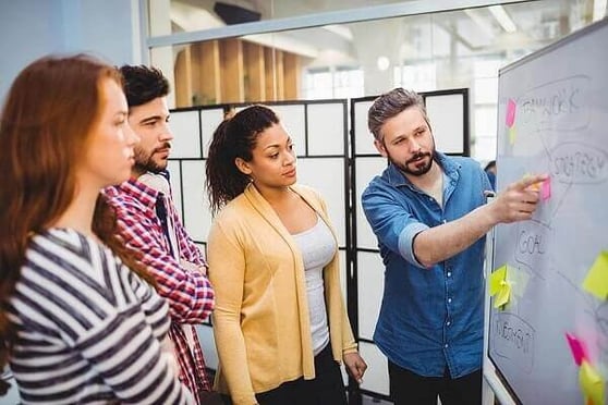 Team brainstorming strategies on a whiteboard, showcasing how to create a digital marketing strategy in action.