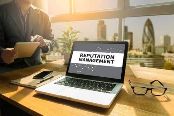 Laptop on a sunny table, the screen says "Reputation Management".