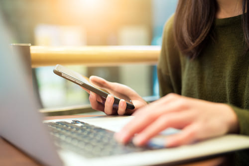 A person using a smartphone and laptop, representing email marketing services for effective communication.