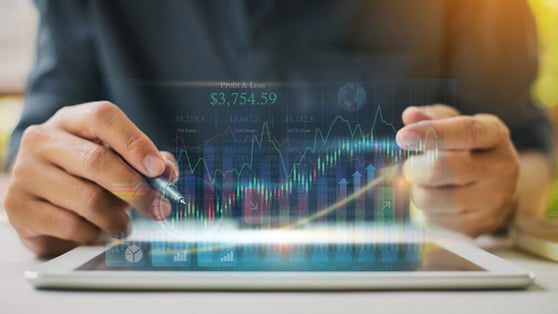 Hands analyzing financial data on a tablet with AI-driven charts and predictive analytics.